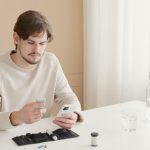 A young man checks his blood glucose level using a glucometer at home.